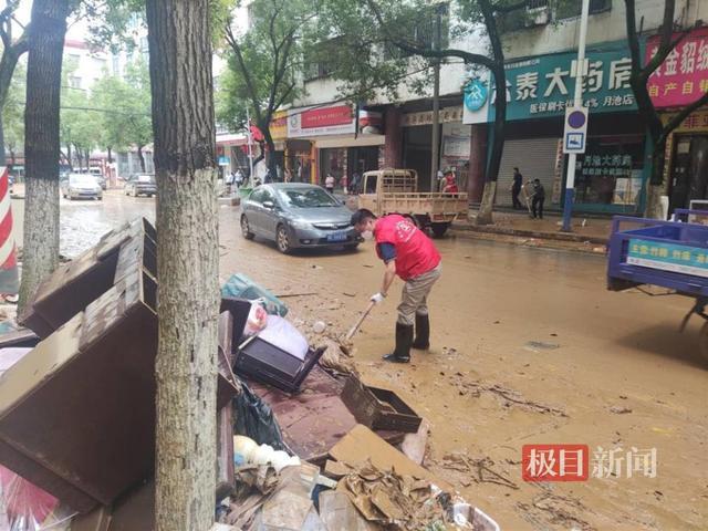 穿红马甲的工作人员在清理淤泥