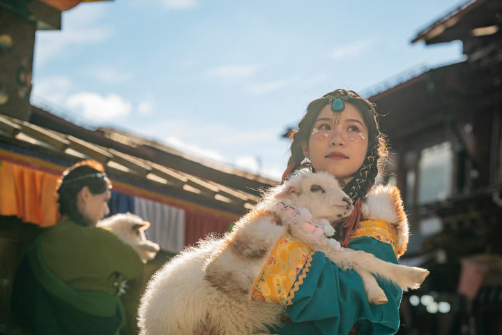 游人在独克宗古城里抱着小羊拍照留念（2023年3月8日摄）。