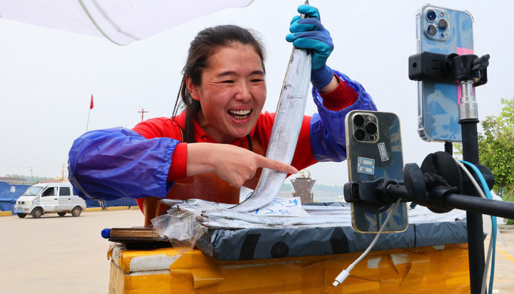 2024年4月22日,连云港市赣榆区下口渔港码头,渔民在直播推介带鱼产品。新华社发(耿玉和 摄)