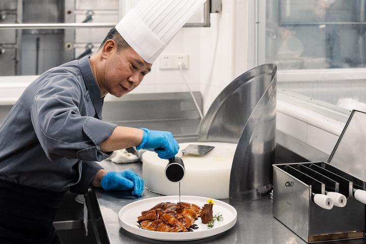 徐锦辉正在餐厅后厨制作玫瑰豉油鸡。