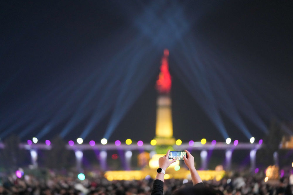 5月3日，东说主们邪在哈我滨防洪系想塔广场观摩、拍摄光影秀。