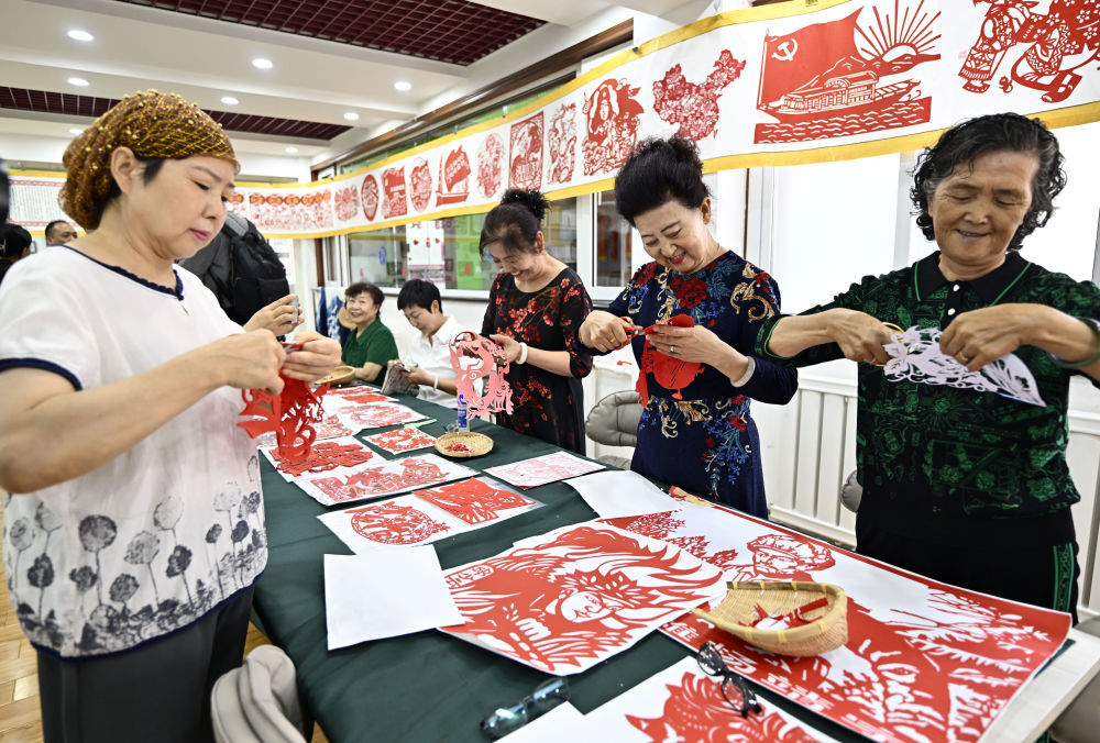 6月19日，长城花园社区居民在社区“才艺堂”制作剪纸。