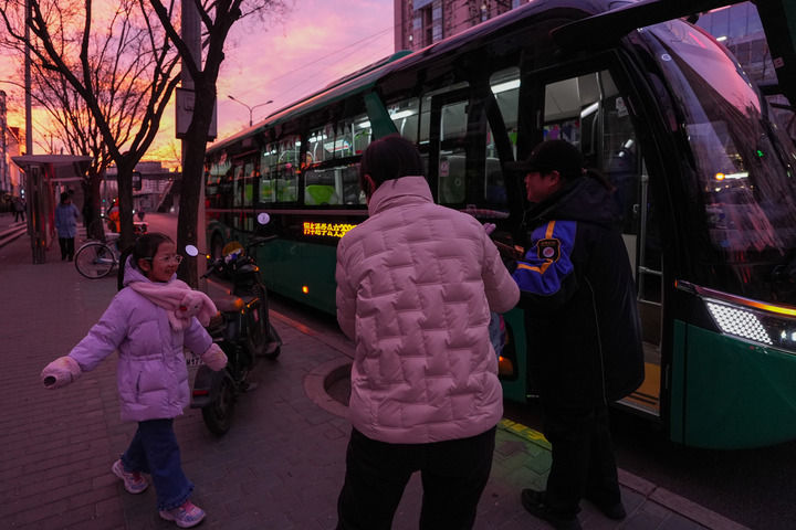 12月16日，在北京市朝阳区朝阳路十里堡通学公交站，通学乘务员徐洁（右一）引导一位小学生上车。新华社记者 鞠焕宗 摄