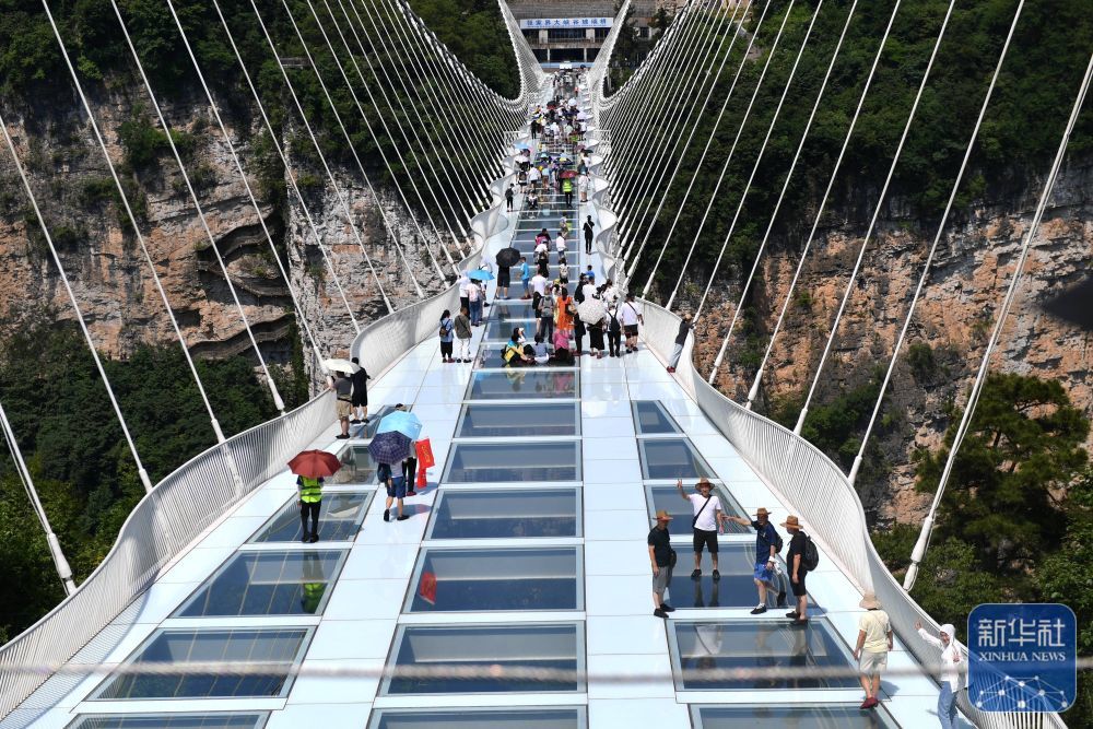 ↑ 这是2022年7月8日，游人在张家界大峡谷玻璃桥游玩。于2016年对外开放的张家界大峡谷玻璃桥，总长430米、宽6米，距谷底相对高度约300米，桥面由99块全透明玻璃铺设。新华社记者 赵众志 摄