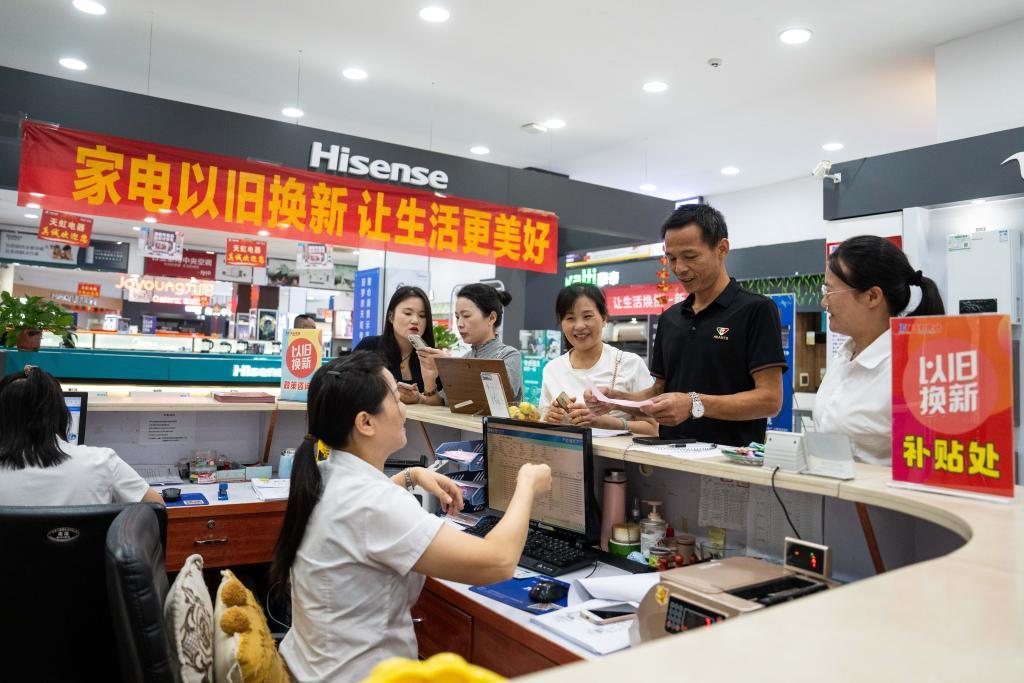 9月24日，在汨罗市天虹电器城，彭坤（右二）参与以旧换新活动后付款购买新电视。新华社记者 陈思汗 摄