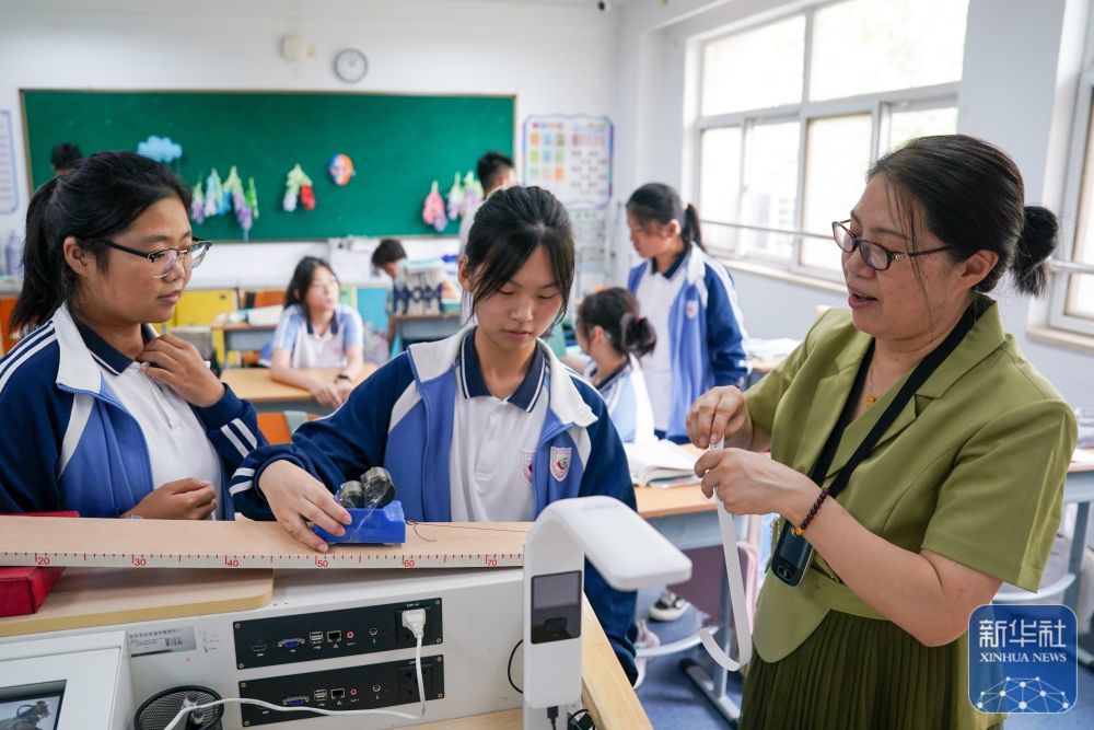 9月3日，在南京市聋人学校，史学军（右一）通过实验为学生演示物理原理。