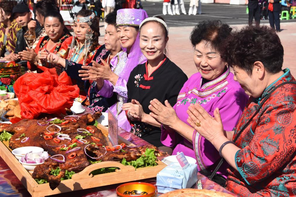 9月27日,在新疆塔城市新城街道哈尔墩社区举行的“邻里节百家宴”现场,居民在品尝各色美食。新华社记者 顾煜 摄