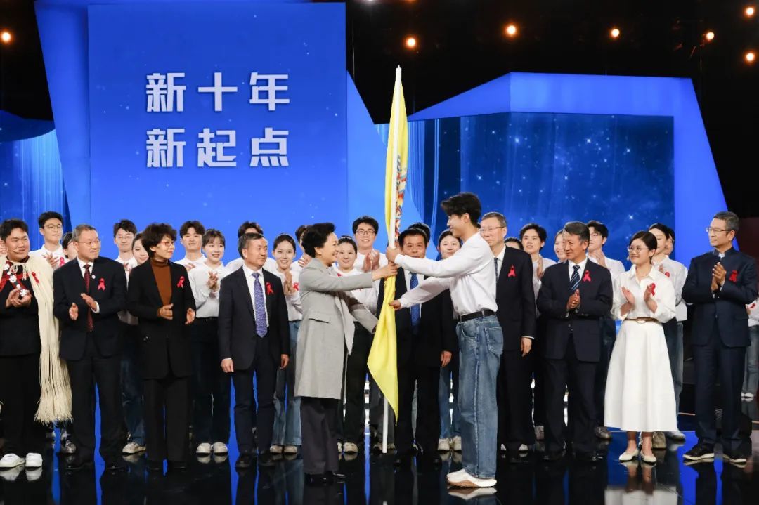 彭丽媛教授为大学生防艾志愿者代表授旗