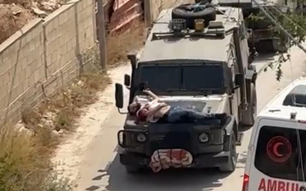 图为当地本领22日，以军将又名受伤的巴勒斯坦男人绑在一辆军用吉普车的引擎盖上带走 图源：酬酢媒体X华贵传的视频截图