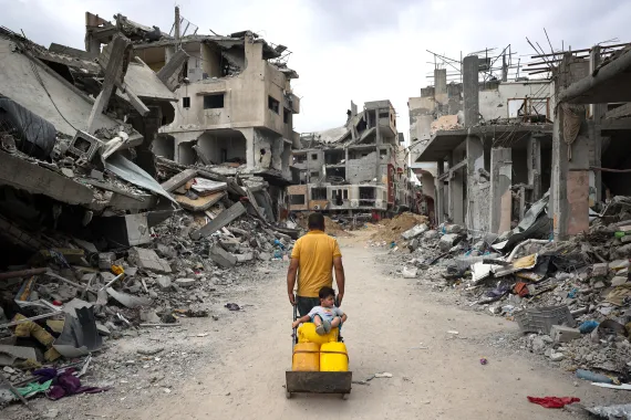 一名巴勒斯坦男子和儿童经过加沙被毁建筑物的废墟 图源：外媒