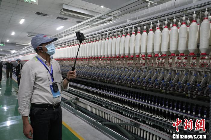 4月13日，外国媒体人参观拍摄新疆尉犁县利华纺织有限公司纺纱厂工作情况。　　徐雪莹 摄