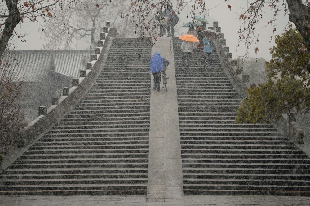 2014年2月18日，行人冒雪从京杭大运河杭州段拱宸桥上走过。