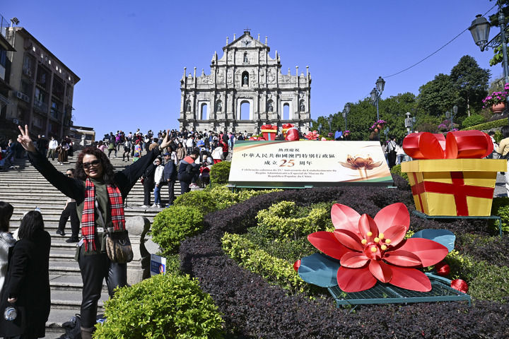 游客在澳门大三巴牌坊庆祝布景旁留影（2024年12月18日摄）。新华社记者 程一恒 摄