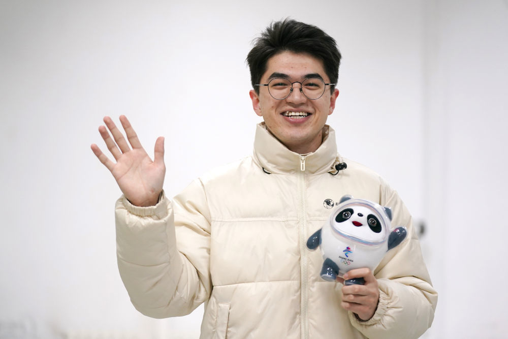 2021年12月15日，学生志愿者艾尔西丁·艾尼瓦尔拿着2022年北京冬奥会吉祥物冰墩墩对着镜头微笑。