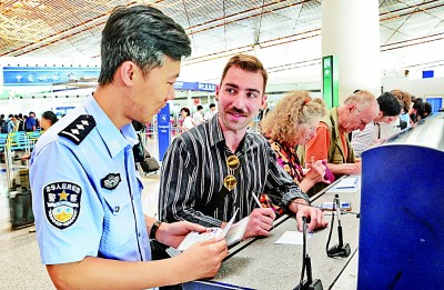 北京首都机场边防检查站的民警协助一名美国游客填写入境登记卡。新华社记者 李欣摄