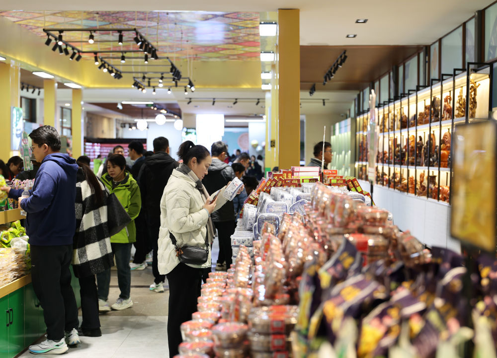 12月15日，在中越德天（板约）瀑布跨境旅游合作区中国一侧的中越旅游商品体验店，游客在选购商品。