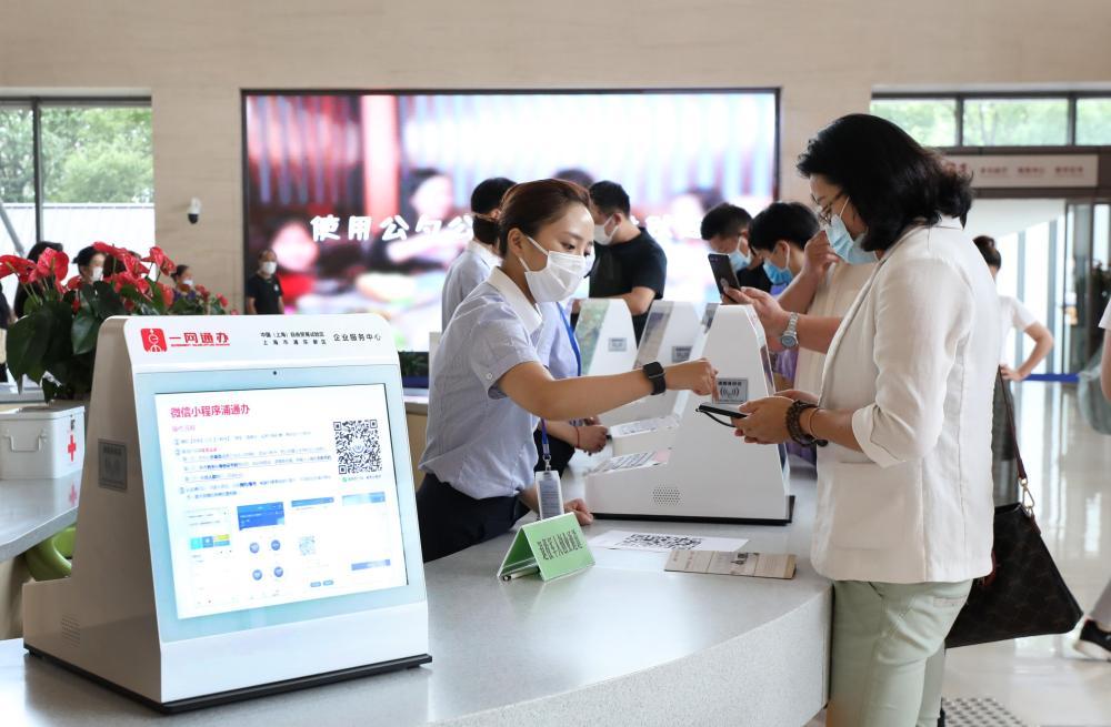 上海市浦东新区2019年率先启动“一业一证”改革。这是在浦东新区企业服务中心办事大厅，工作人员指导市民通过手机小程序办理一网通办业务（2020年8月4日摄）。