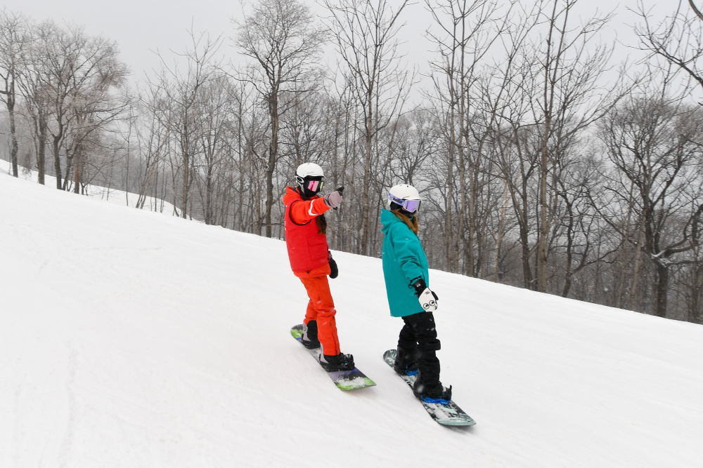 ↑2023年11月23日，滑雪教练王雪（左）在北大湖滑雪度假区教学员滑雪。新华社记者 张楠 摄