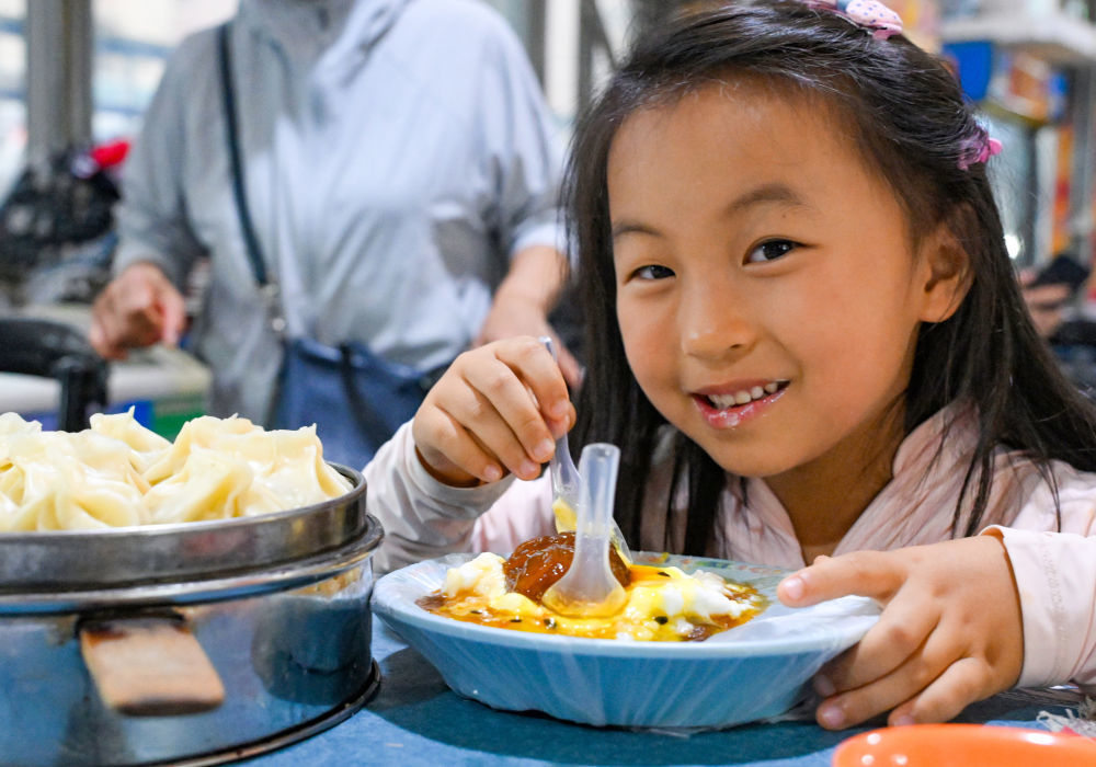 来自上海的小朋友在和田夜市品尝酸奶粽子。