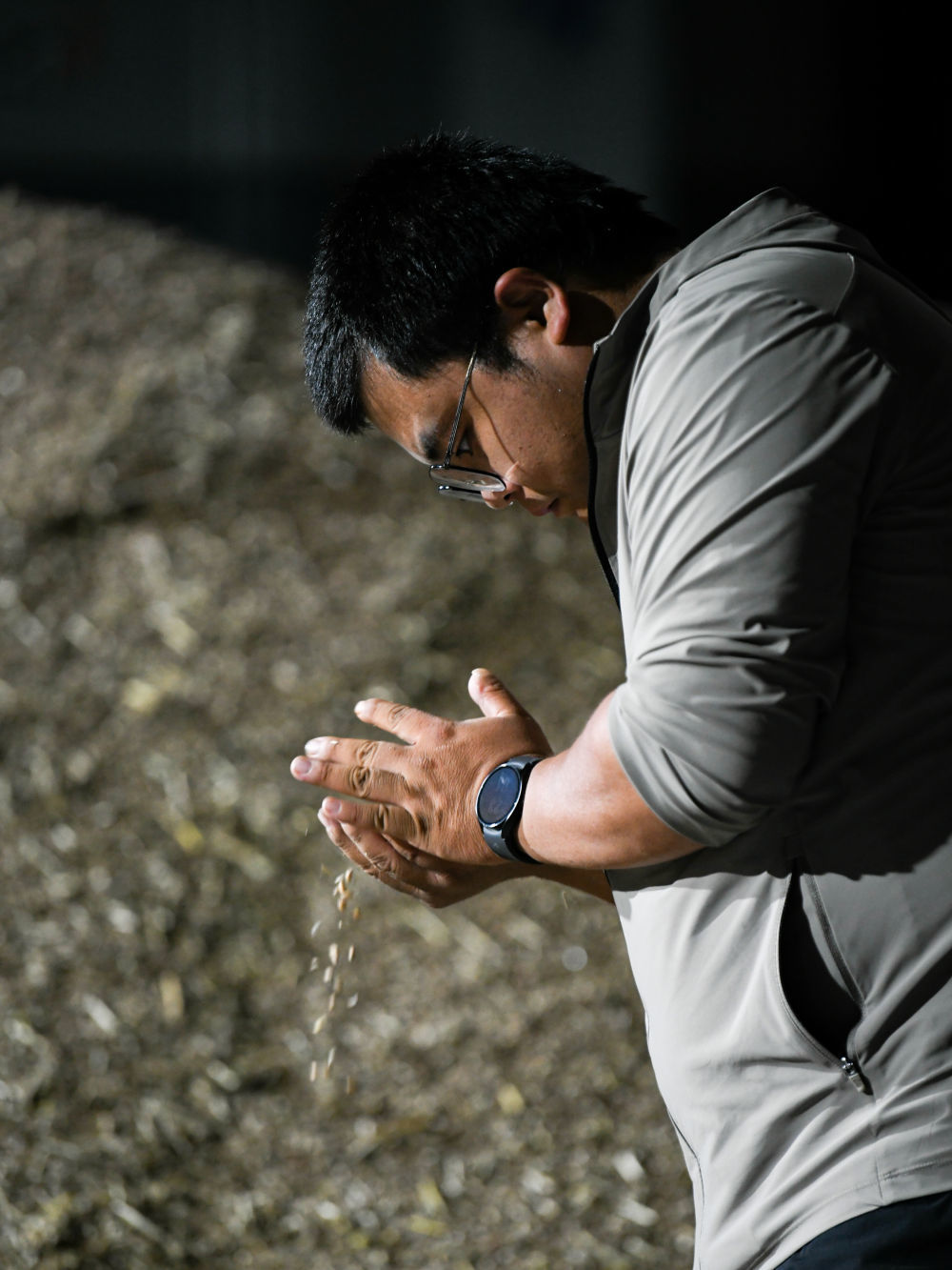 在四川成都崇州市万茂欣欣农机专业合作社，舒星宇在查看库房待烘干小麦的情况（5月15日摄）。