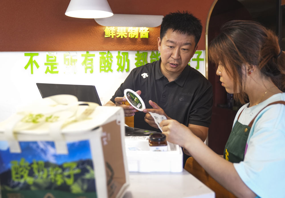 在乌鲁木齐，博斯坎酸奶粽子品牌创始人张磊（左）在门店与工作人员沟通如何搭配礼盒内容。