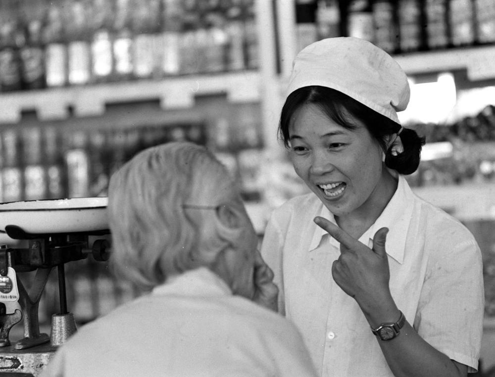1985年，北京东直门外食品店售货员王焕贵向顾客耐心介绍商品。