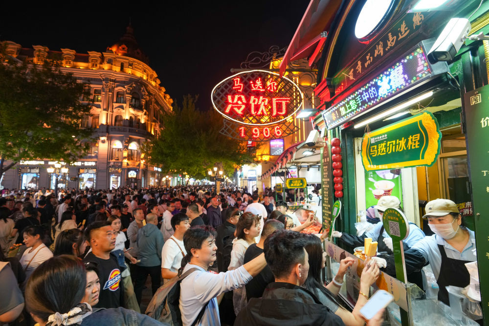 5月3日，游客在哈尔滨中央大街上的马迭尔冷饮厅购买冰棍。