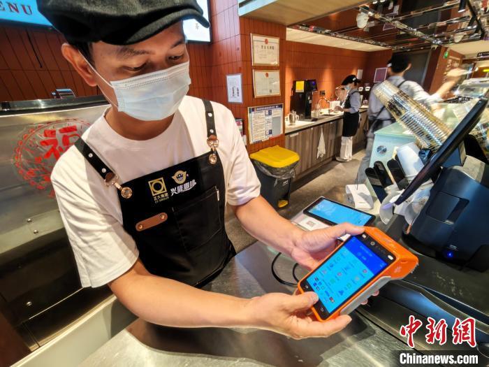 6月13日，太阳河兴隆咖啡海口骑楼店店长符传贵展示可受理外卡刷卡的智能POS机。中新社记者 　王子谦 　摄