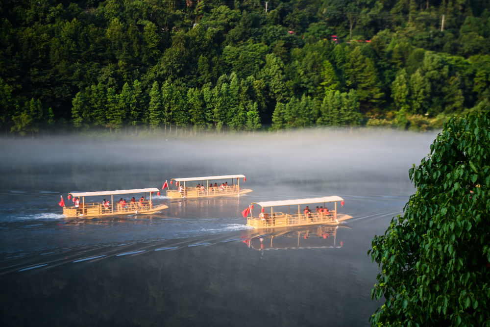 2023年7月16日清晨，游客乘坐“竹筏”造型电动游船，在浙江建德新安江的江雾中前行。新华社记者 徐昱 摄