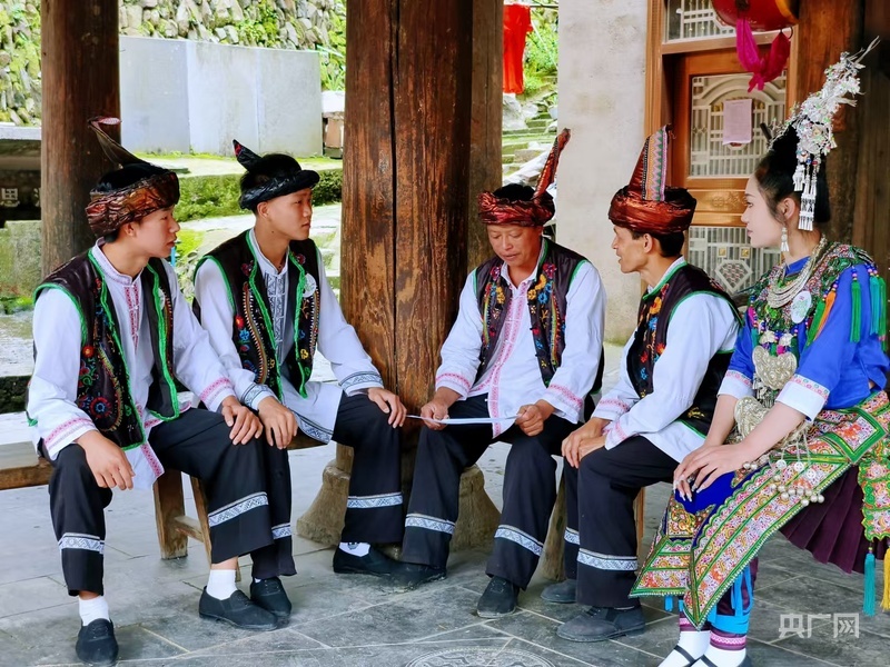 聂和香（右一）在鼓楼与村民共商侗寨文旅传承（央广网记者 栾小琳 摄）