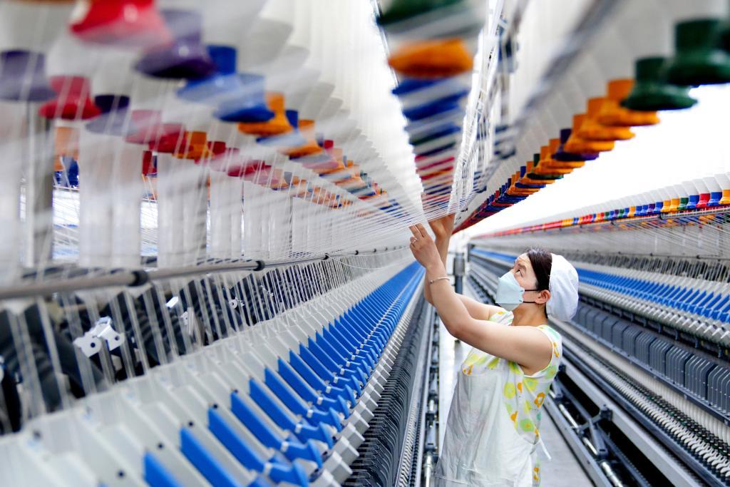 3月12日，在山东腾峰纺织科技有限公司，工作人员在智能化纺纱设备前忙碌。新华社记者郭绪雷摄