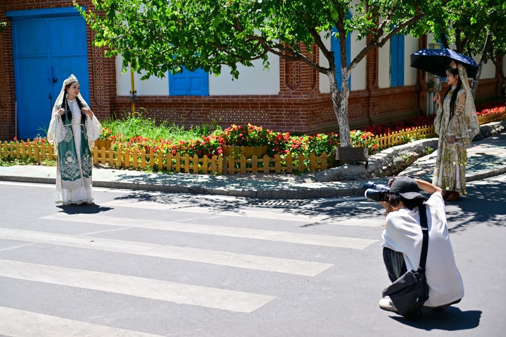 在伊犁哈萨克自治州伊宁市六星街，游客体验旅拍项目（7月27日摄）。