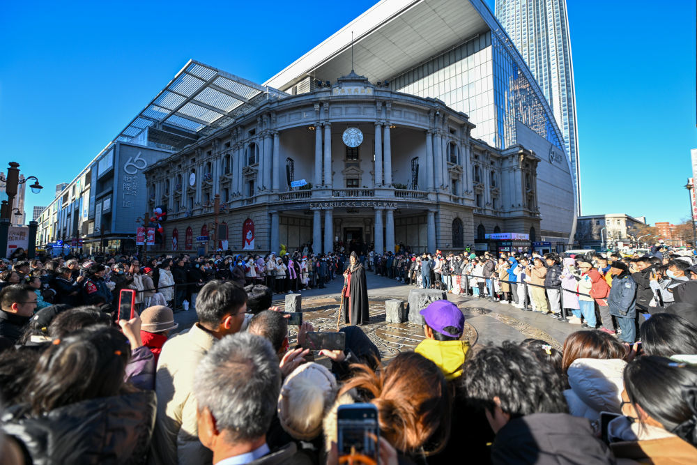 ↑市民游客在天津金街大铜钱广场观看天津人民艺术剧院带来的沉浸式戏剧演出（12月21日摄）。