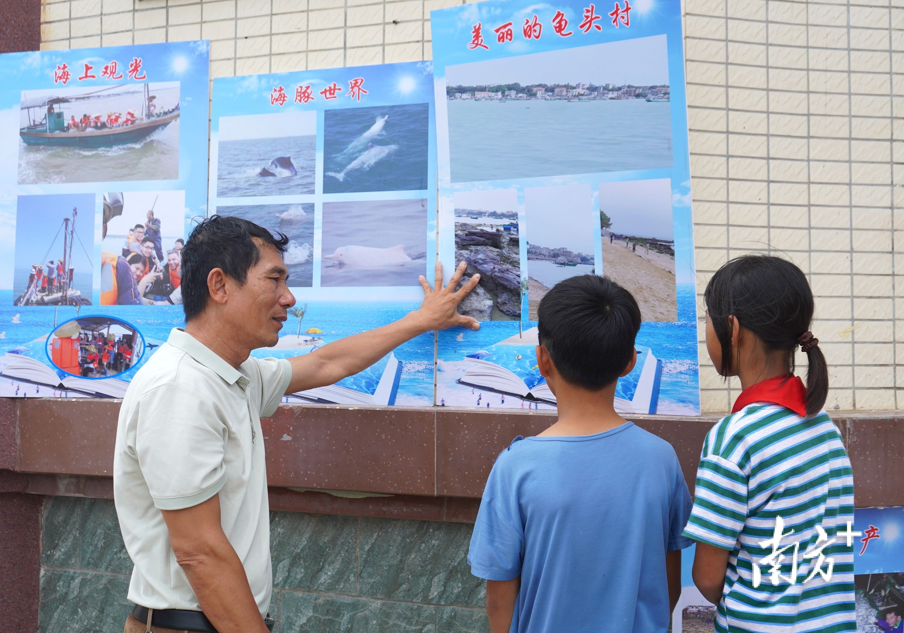 湛江东海岛龟头村村民庄宏清给村内的小朋友讲解如何保护白海豚。