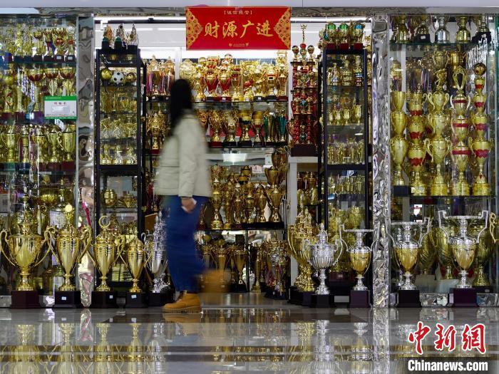 2024年4月10日，一位采购商路过浙江义乌国际商贸城专售奖杯的店铺。董易鑫 摄