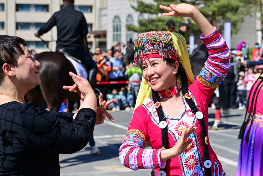 ↑4月30日，在新疆乌鲁木齐市举行的巡游活动上，市民和游客一起跳麦西来甫。