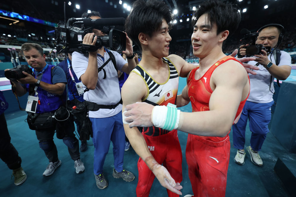 ↑7月29日,在体操男子团体决赛中,中国队选手张博恒(右二)在单杠比赛后与日本队选手桥本大辉(右三)相互致意。