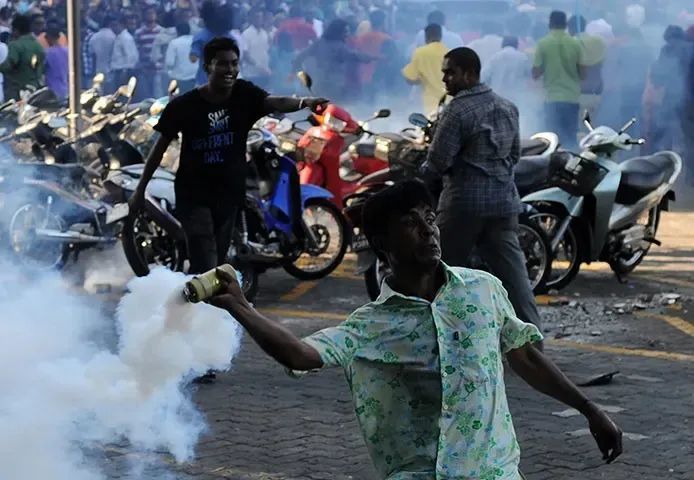 ◆2012年马尔代夫爆发骚乱，一名反政府抗议者向警察投掷催泪瓦斯罐。
