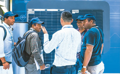 图为参展商在第135届广交会上向非洲采购商介绍太阳能电池组件展品。新华社记者 刘大伟摄