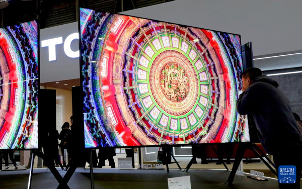 3月14日，一名参观者在TCL公司展台上近距离观察一款电视展品的屏幕。图源：新华社