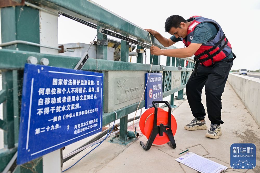 ↑在新疆阿克苏地区沙雅县盖孜库木乡，阿克苏水文勘测局的工作人员在盖孜库木大桥防洪段收集水文信息（8月3日摄）。新华社记者 丁磊 摄