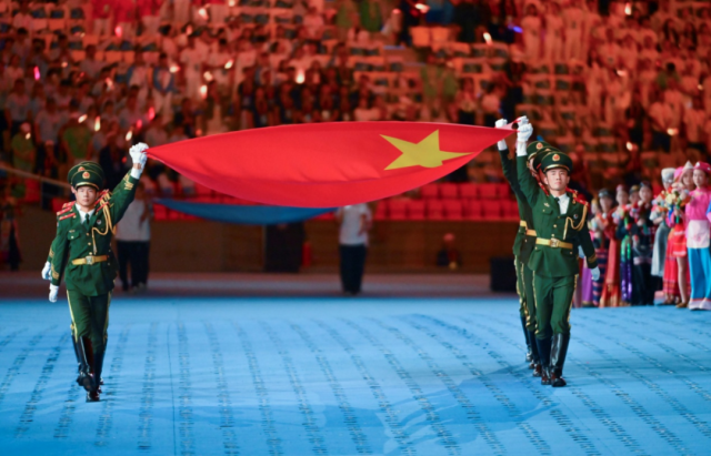 图为开幕式上，国旗护卫队护送五星红旗入场