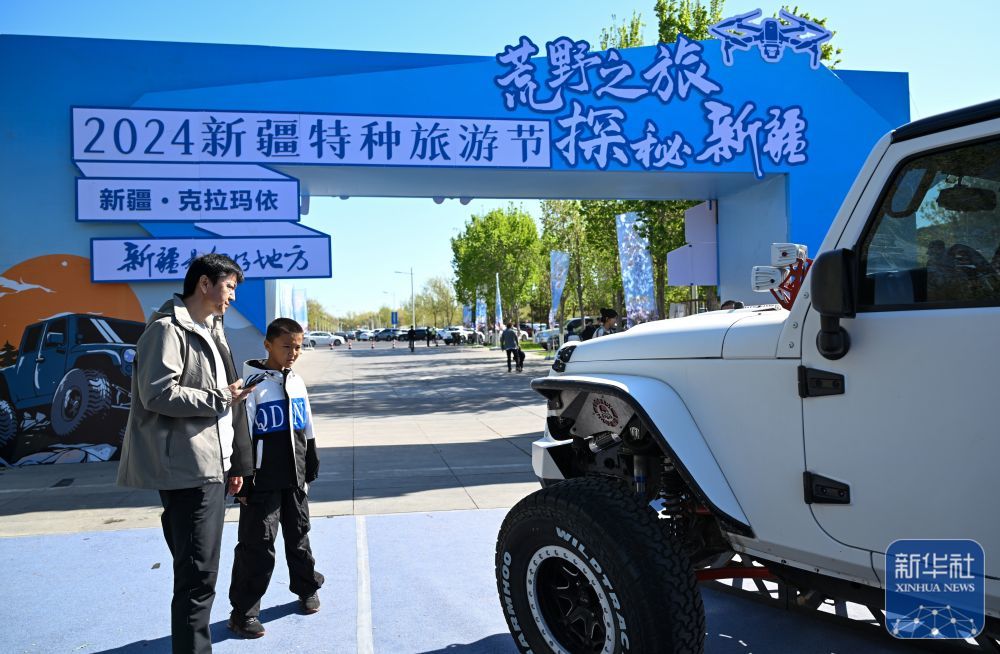 ↑4月27日，在新疆特种旅游节特种旅游装备展上，游客在了解拉力赛车辆。