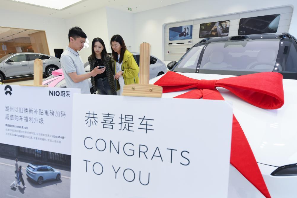 9月24日，在位于湖州市湖东街道的蔚来交付中心，销售人员向顾客介绍提车后如何申领以旧换新补贴。新华社记者 翁忻旸 摄