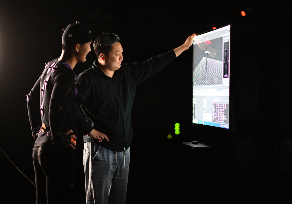 崔盛辑（右）和同事马鑫琪在动作捕捉棚内查看电脑生成的虚拟角色动作（4月23日摄）。