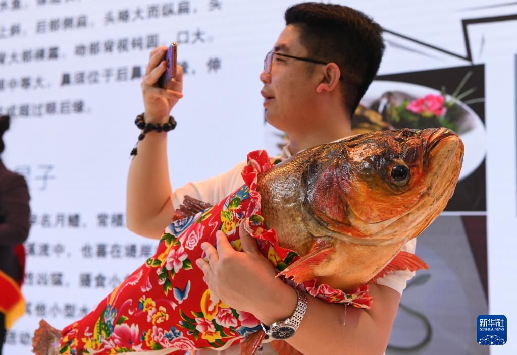 5月20日，在第八届中俄博览会上，参会人员展示从黑龙江、松花江、乌苏里江三江汇流处捕捞的胖头鱼。（图源：新华社）