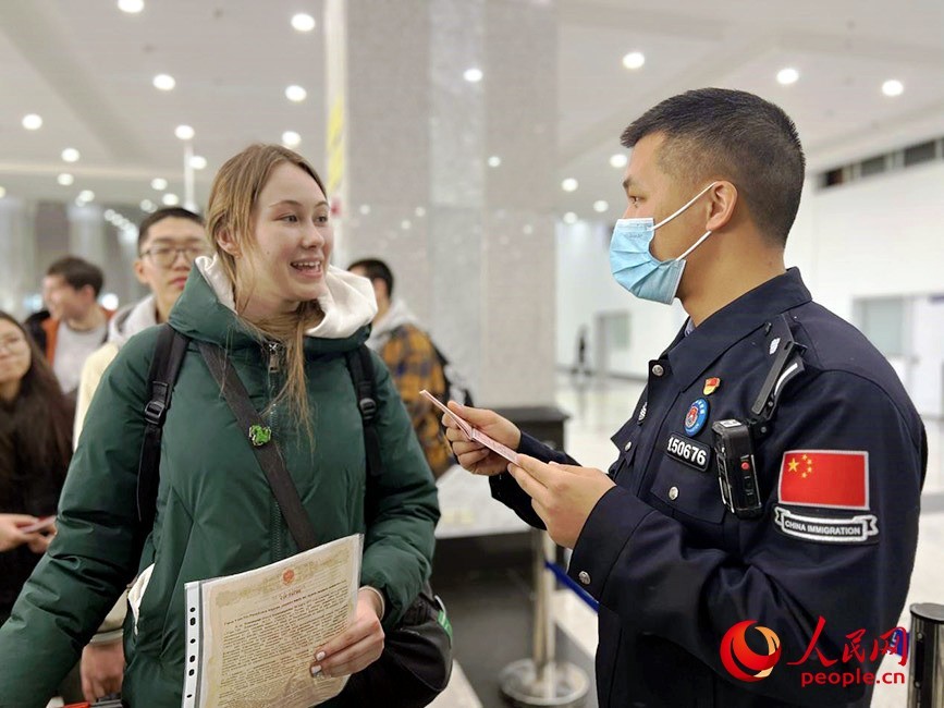 梅小兵(右一)正在查验旅客证件。郭慧芳摄