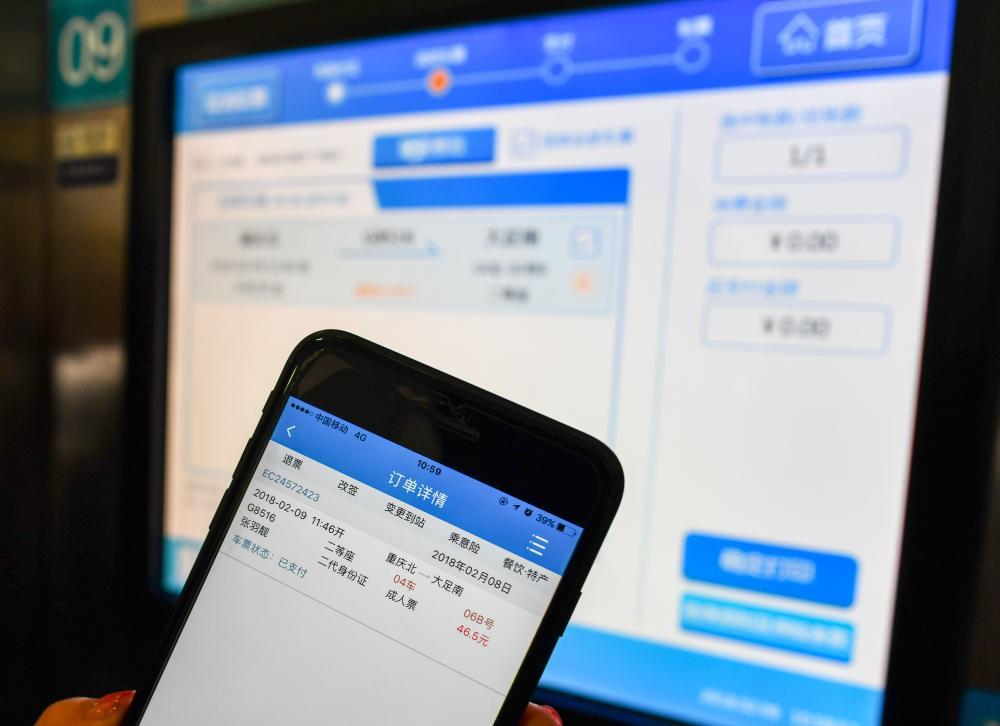 2018年2月9日，旅客在重庆火车北站的自助设备上取出用手机APP预订的火车票。新华社记者 刘潺摄