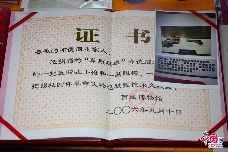 ▲草原英雄布德故居内景·捐赠证书(手枪是1960年周恩来总理接见布德时的赠送)。中国网记者郑伟摄
