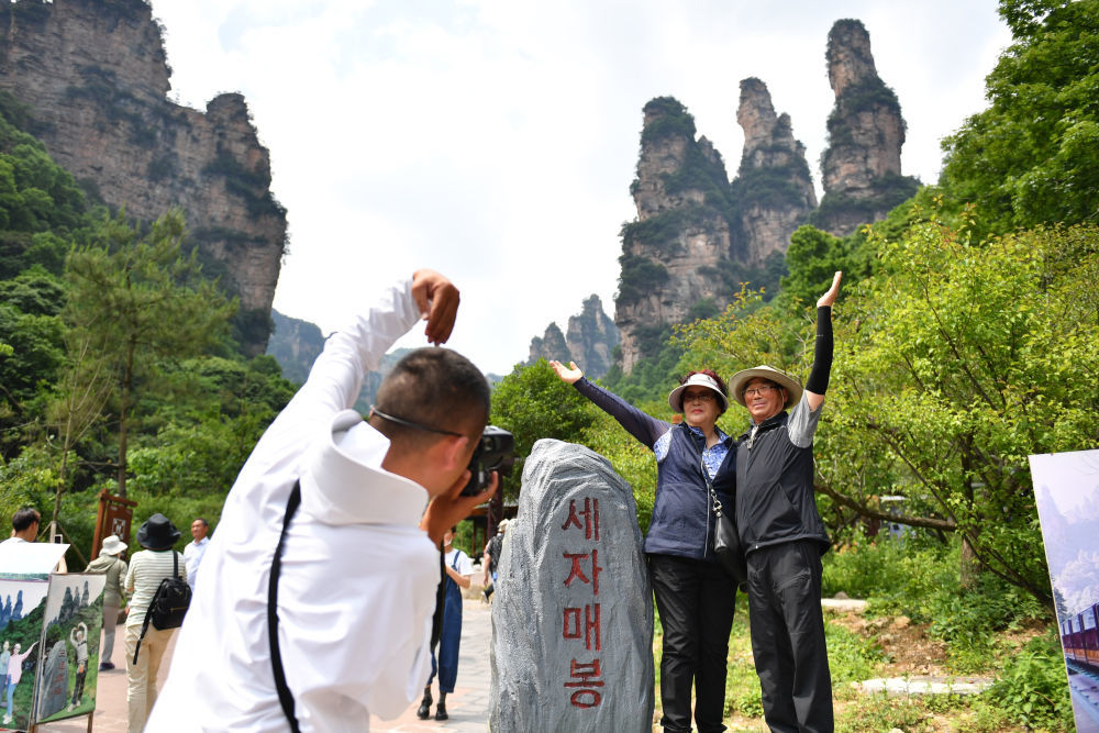 5月22日，在张家界国家森林公园十里画廊景区，韩国游客在“三姐妹峰”前拍照留影。新华社记者 陈振海 摄